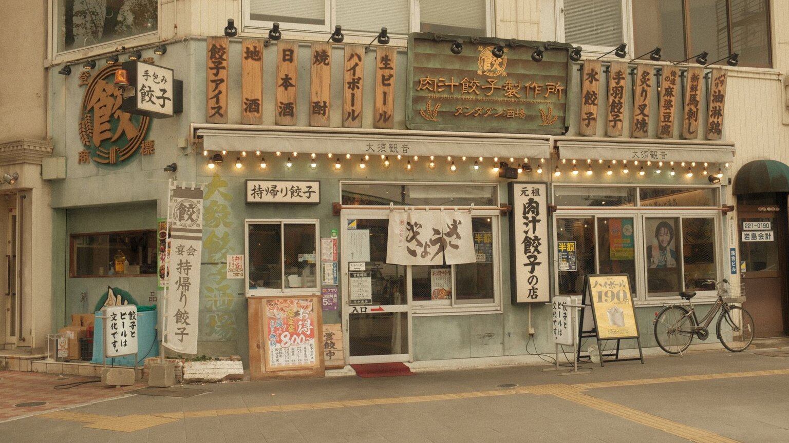 The front of a gyoza restaurant in Japan, with signs, menus and a noren curtain almost entirely in Japanese
